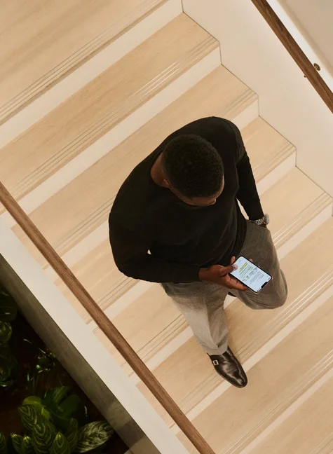 Above-view of a person walking down the stairs while using the reMarkable app on their phone.