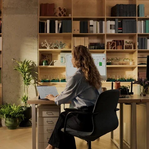 A person sitting at their office desk, writing on a type folio attached to their reMarkable Paper Pro.