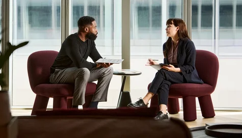 Two people sitting and engaged in a discussion, each holding a reMarkable Paper Pro.