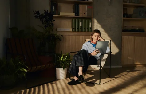 A person sitting in a relaxed chair in an clean and organized office, holding her reMarkable Paper Pro while reading.