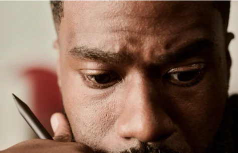 Close-up of a focused person holding a Marker Plus while resting their face on their palm.