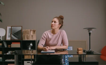 A woman sitting behind a desk writing on a reMarkable Paper Pro with Marker Plus.